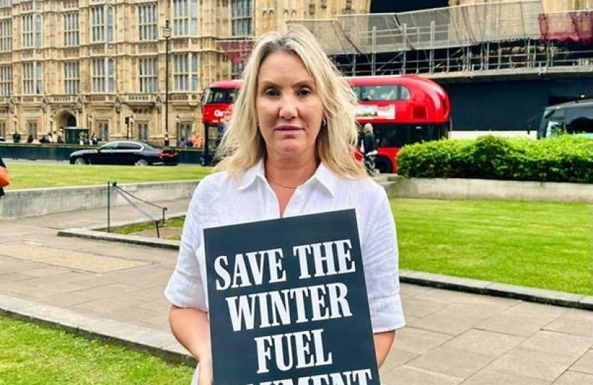 Dame Caroline Dinenage MP holding a sign that states 'Save the Winter Fuel Payment'