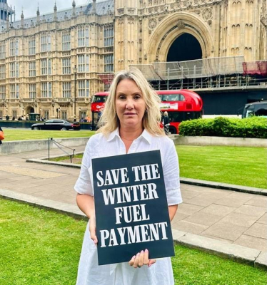 Dame Caroline Dinenage MP holding a sign that states 'Save the Winter Fuel Payment'